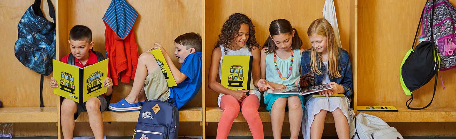 five students sitting in cubbies looking at each other's yearbooks